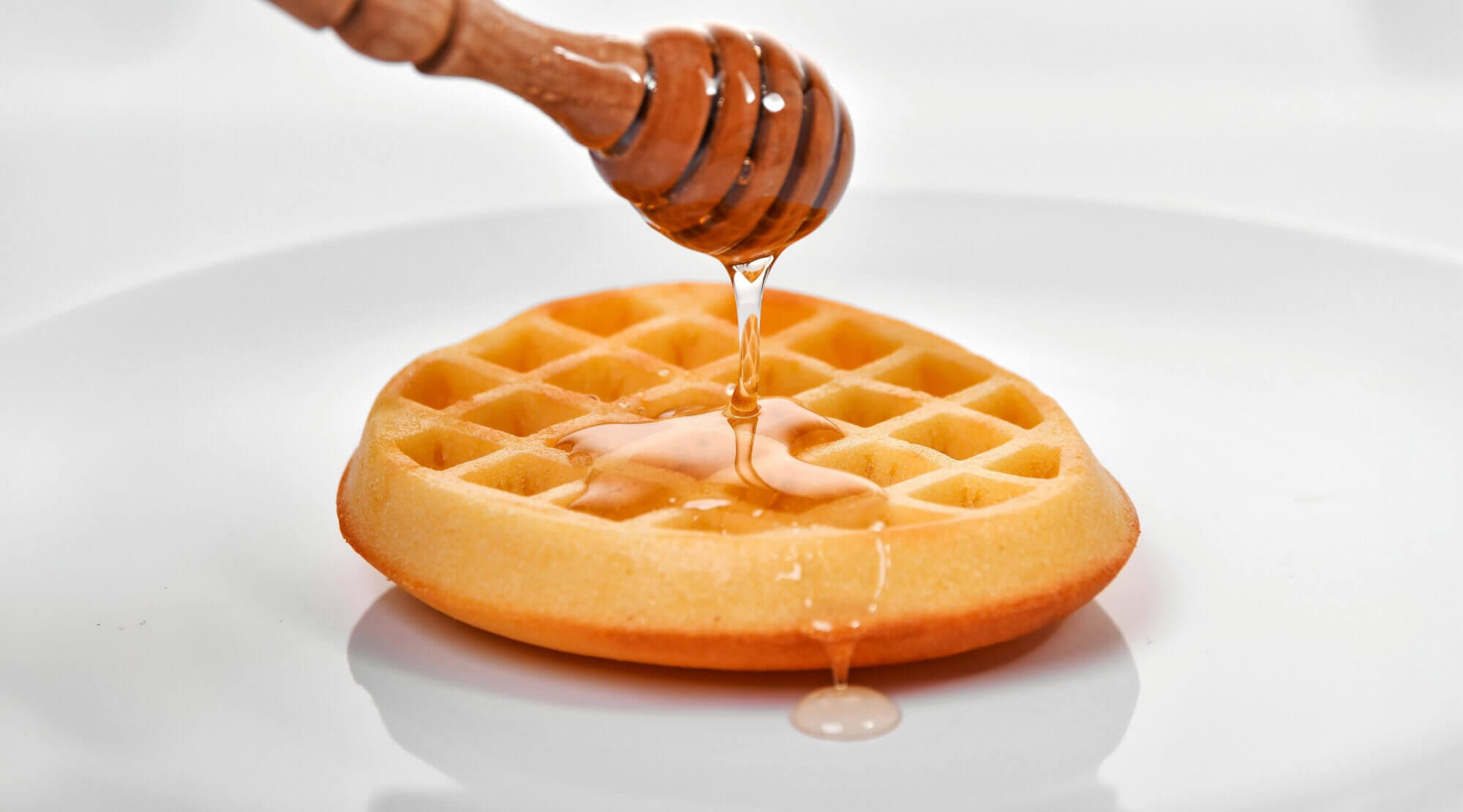 Syrup being poured on waffles.