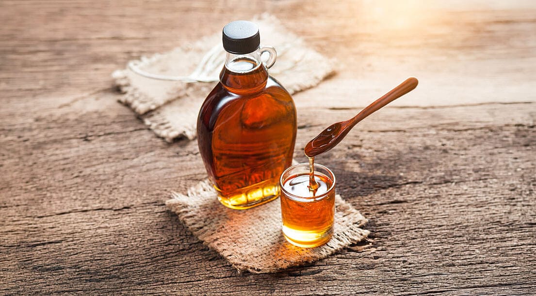 Maple syrup ladled with a spoon into a cup.
