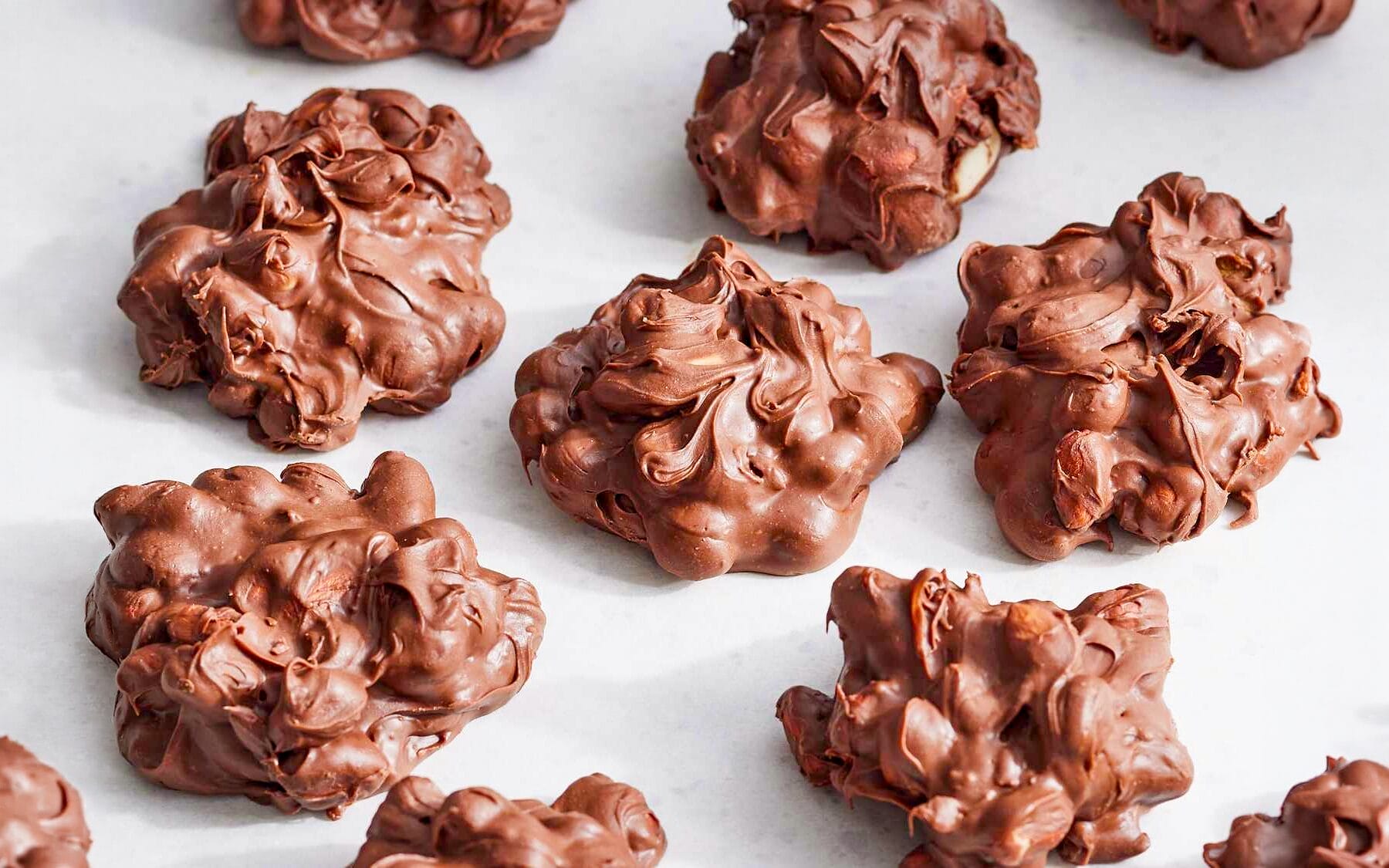A bunch of Peanut Clusters laid out on a parchment paper.