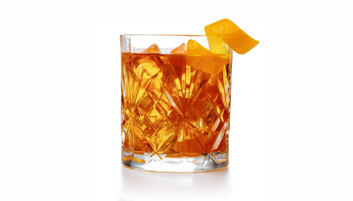 Whiskey in a cup with a orange peel twist.