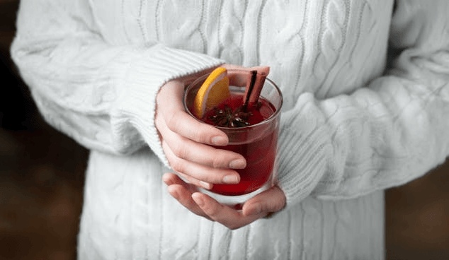 Woman holding a glass of Mulled Wine.