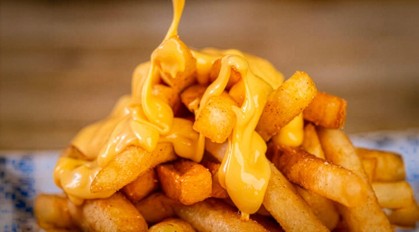 Pouring cheddar cheese on fries